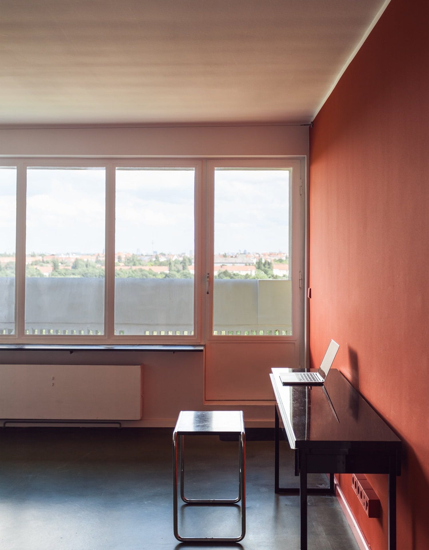 Appartement im Corbusierhaus, Berlinrote Wandschwarzer SchreibtischStuhlHockerFenster