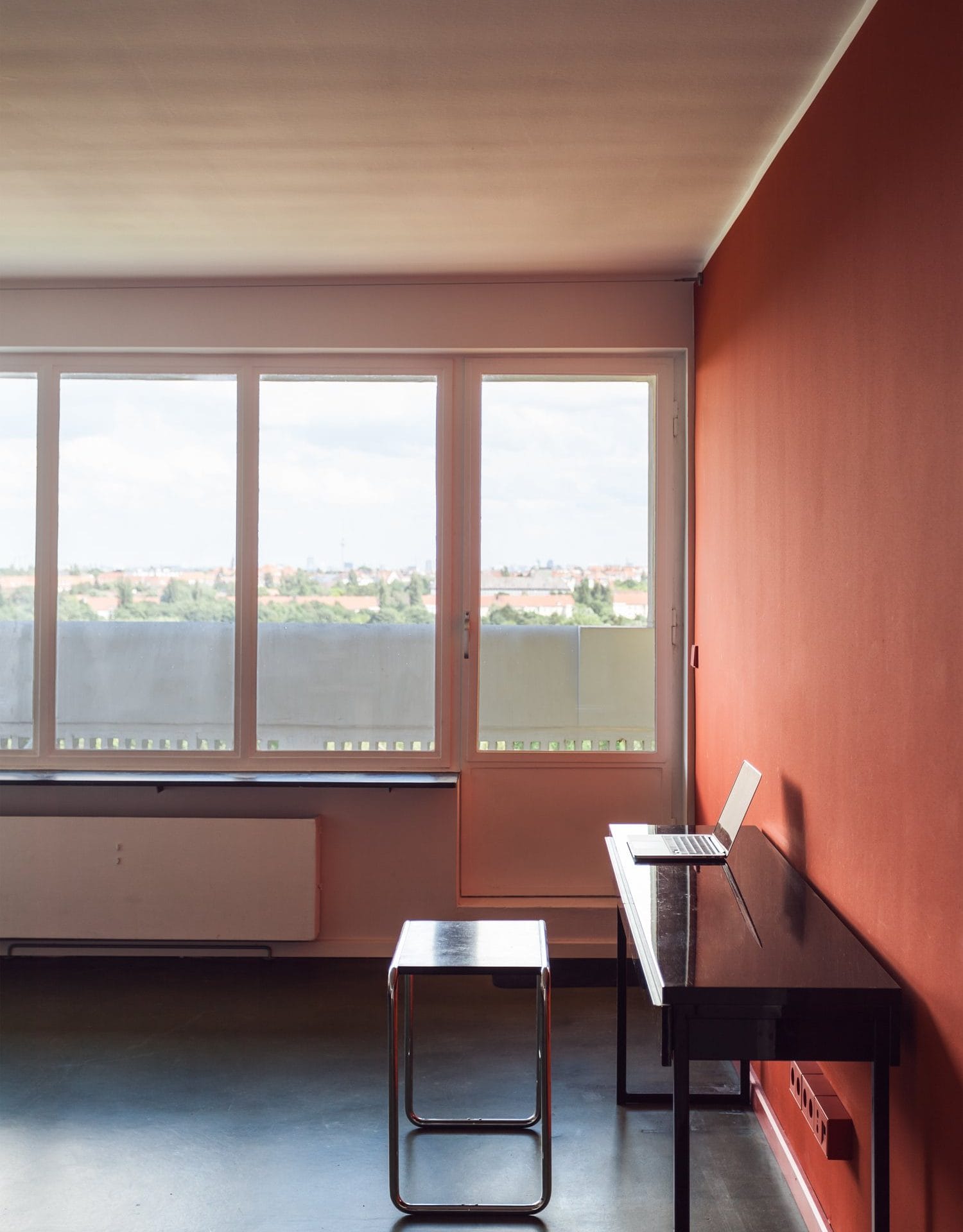 Appartement im Corbusierhaus, Berlinrote Wandschwarzer SchreibtischStuhlHockerFenster